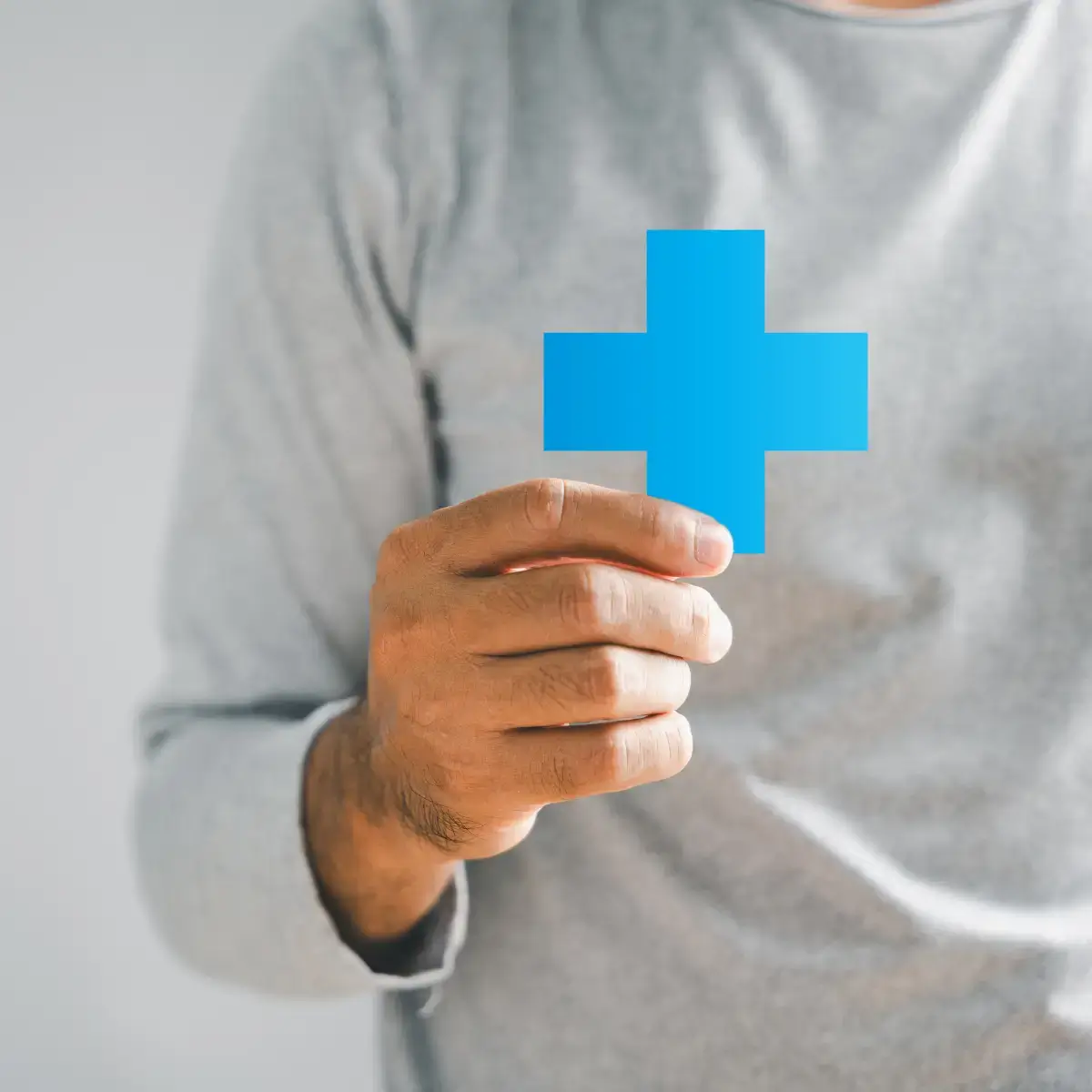 Mão de profissional de saúde a segurar cruz médica azul