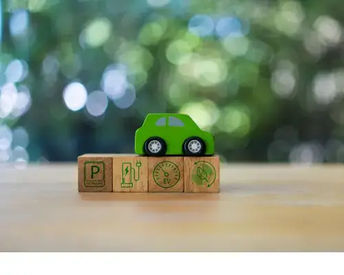 Carro verde em miniatura sobre cubos de madeira com símbolos ecológicos