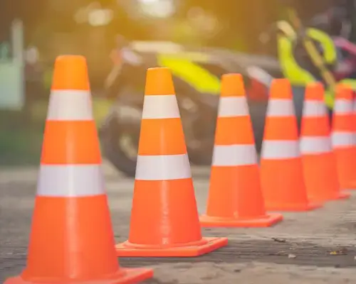 Cones de trânsito laranja e brancos alinhados numa estrada em obras